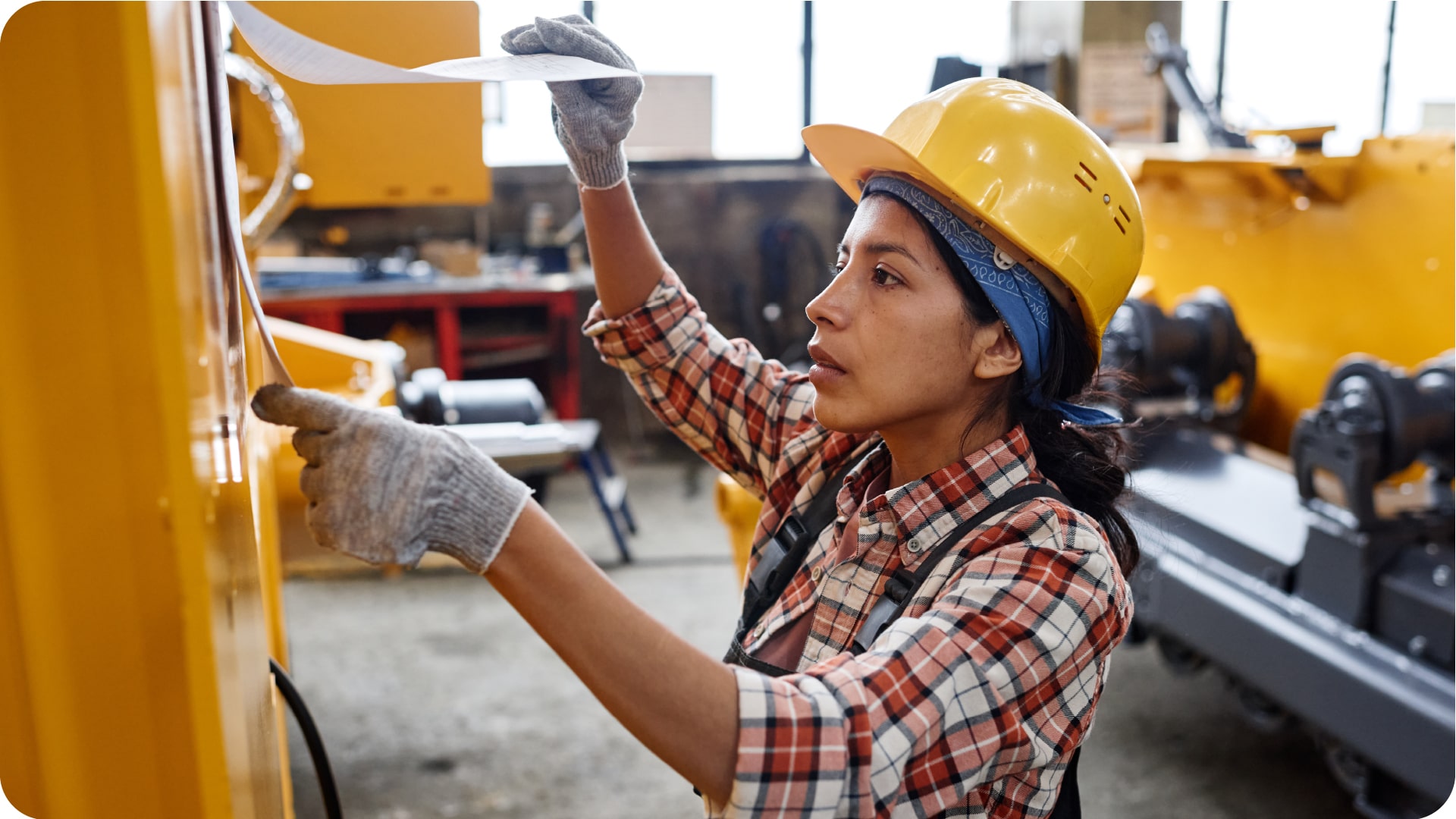 Mulher utilizando equipamentos de proteção verificando lista em equipamento. Este processo é importante para a investigação de acidentes de trabalho.