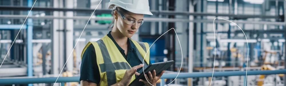 Trabalhadora usando EPIs com um tablet nas mãos.